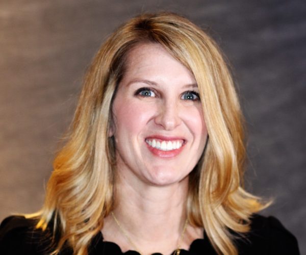 Headshot of Liz smiling with blond hair and a black shirt