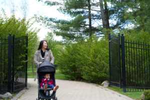 Bo Zhao walking with her toddler daughter in a stroller on a stone path through greenery. Credit: Cham Zhao 